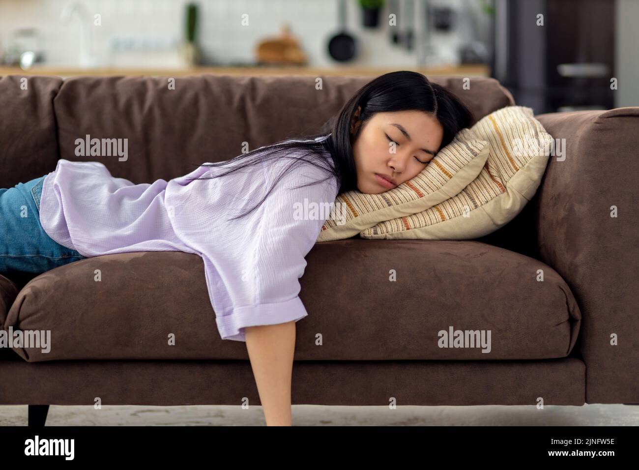 Tired caucasian young woman falls asleep on couch on the couch after