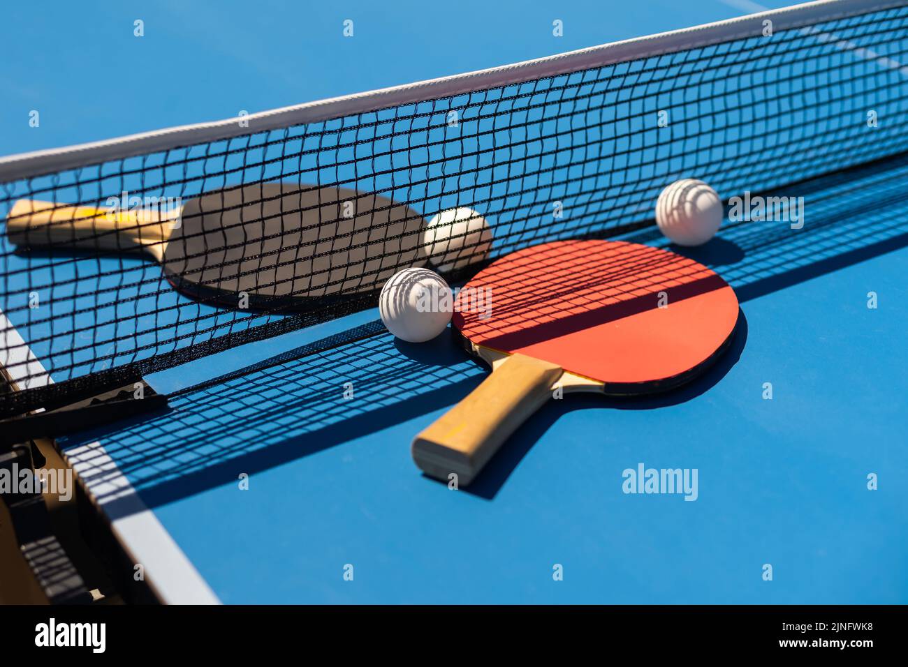 Table tennis rackets and a white plastic ball on a blue background ...