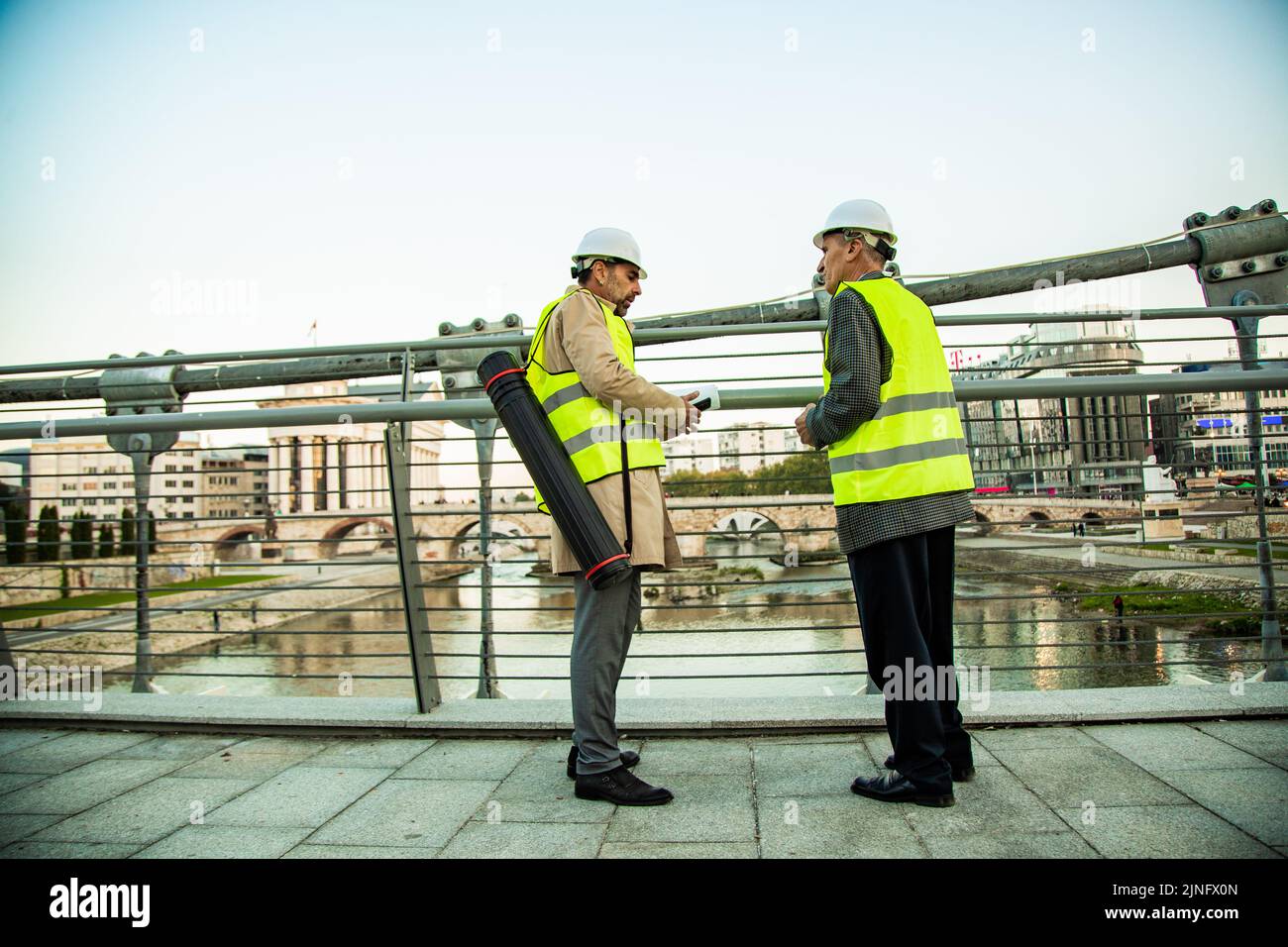 Two senior construction managers are standing on the bridge while talking Stock Photo