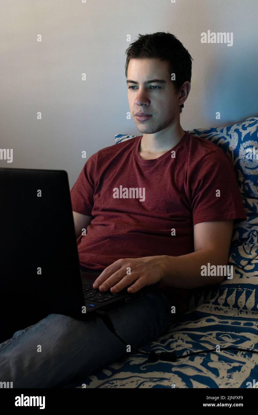 Teenager sitting on bed using laptop