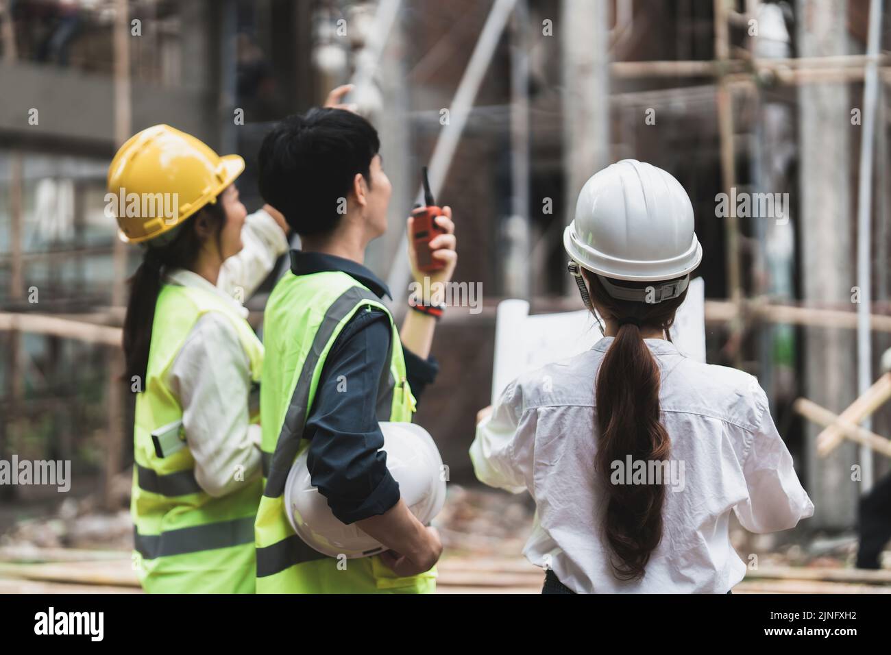 engineering and construction managers discussing project blue print on the table at construction site Stock Photo