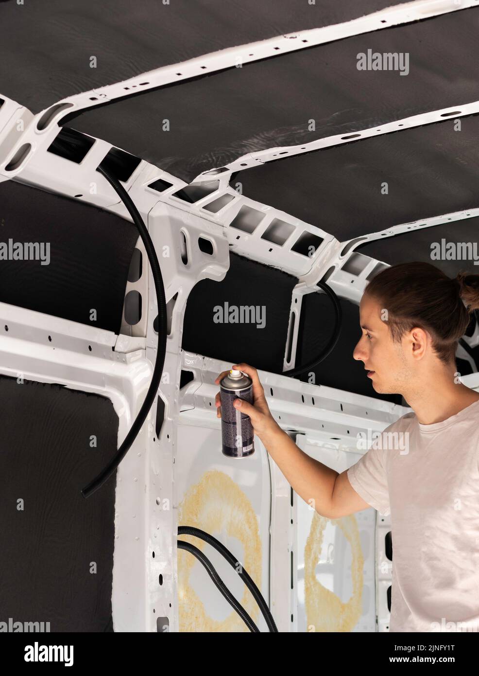 Vertical view of young man using a spray paint bottle to paint the