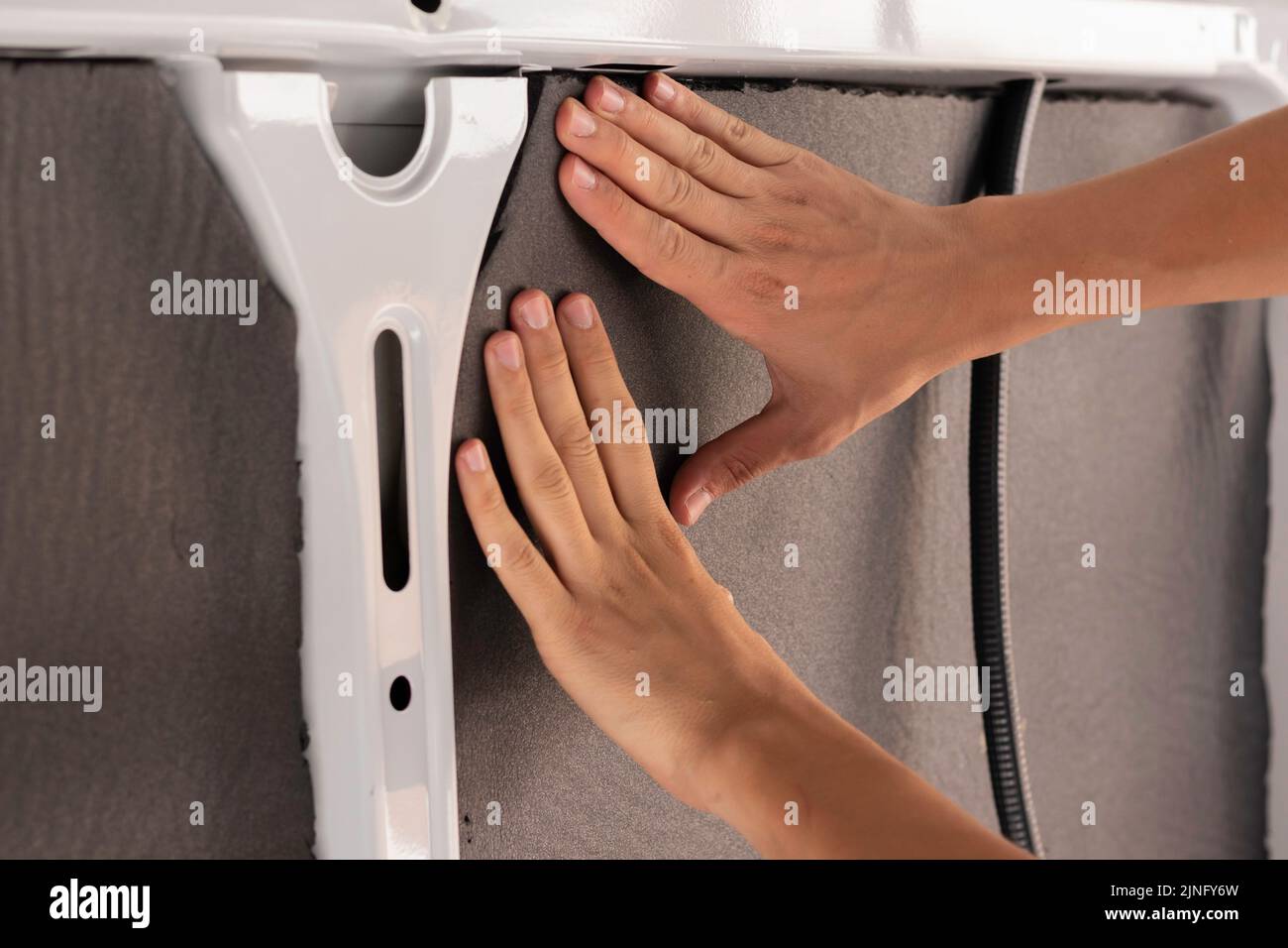 Close up view of unrecognizable young man hands placing and installing the isolation of a camper van convertion order Stock Photo