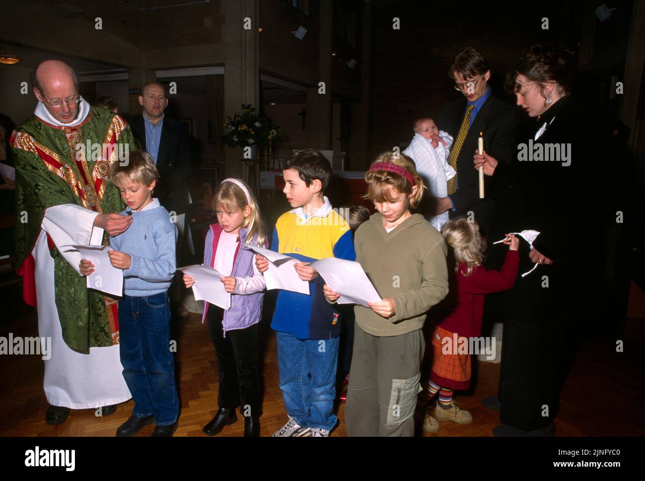 Priest Holding Microphone to Children as they are Reading Prayers at Christening in St Bernard's Catholic Church Surrey England Stock Photo
