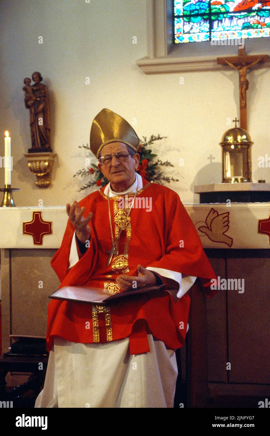 Bishop At Pentecost Service giving Sermon while Sitting Down a at St Ann's Catholic Church Kingston London England Stock Photo