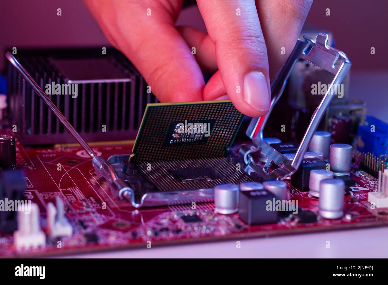 A man's hand inserts a processor into the motherboard socket Stock ...