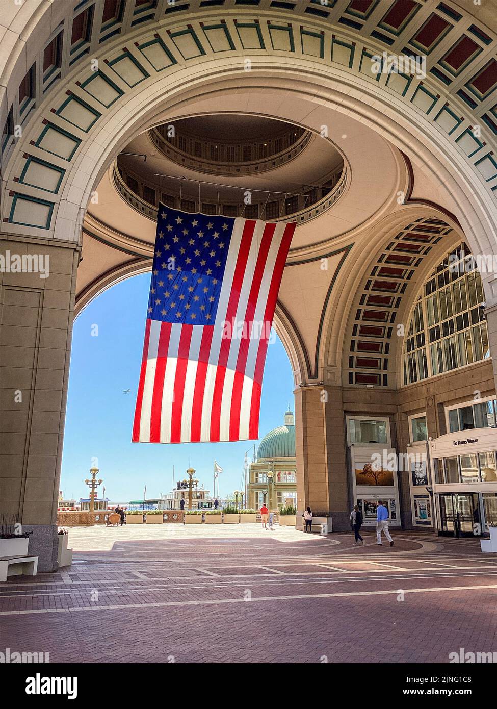 A giant American Flag hangs from the arch and buildings at Rowes Wharf in Boston, Massachusetts Stock Photo