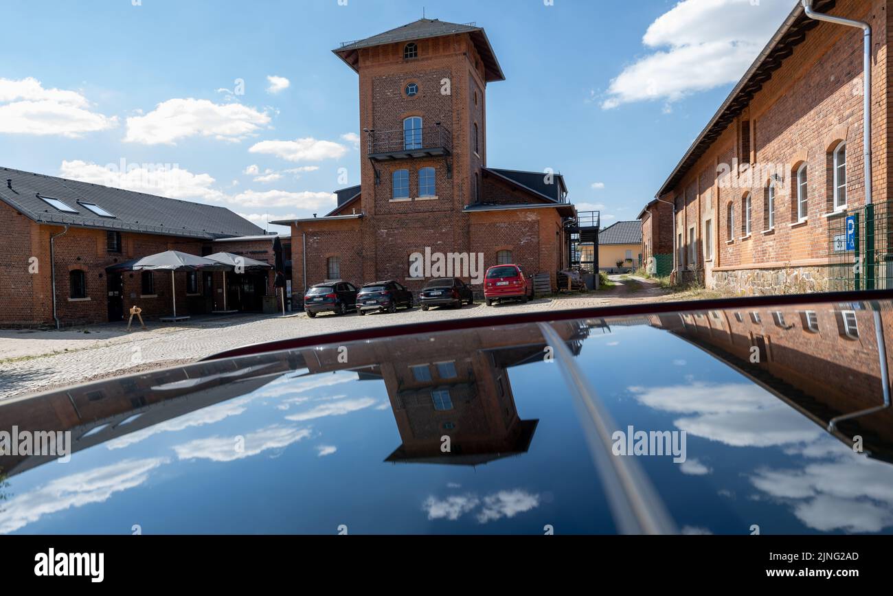 11 August 2022, Saxony, Stollberg: The Old Slaughterhouse in Stollberg is reflected in a car roof. Today, the industrial building is used as a venue for concerts, workshops and projects. The town, which has a population of around 11,500 and is located on highway 72, has a number of examples of how millions in federal and state funding have been used to create new things or renovate old buildings and put them to new uses. Since the beginning of the 1990s, around 6.2 billion euros have flowed into Saxony's cities from the federal and state governments for urban redevelopment. Photo: Hendrik Schm Stock Photo