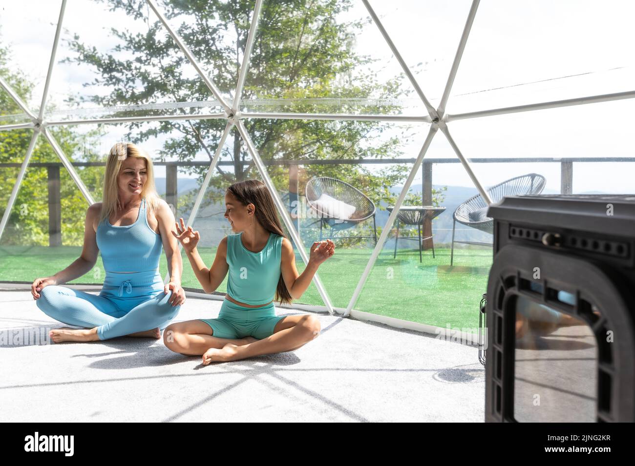 mother and daughter doing yoga and meditation indoor in a glamping
