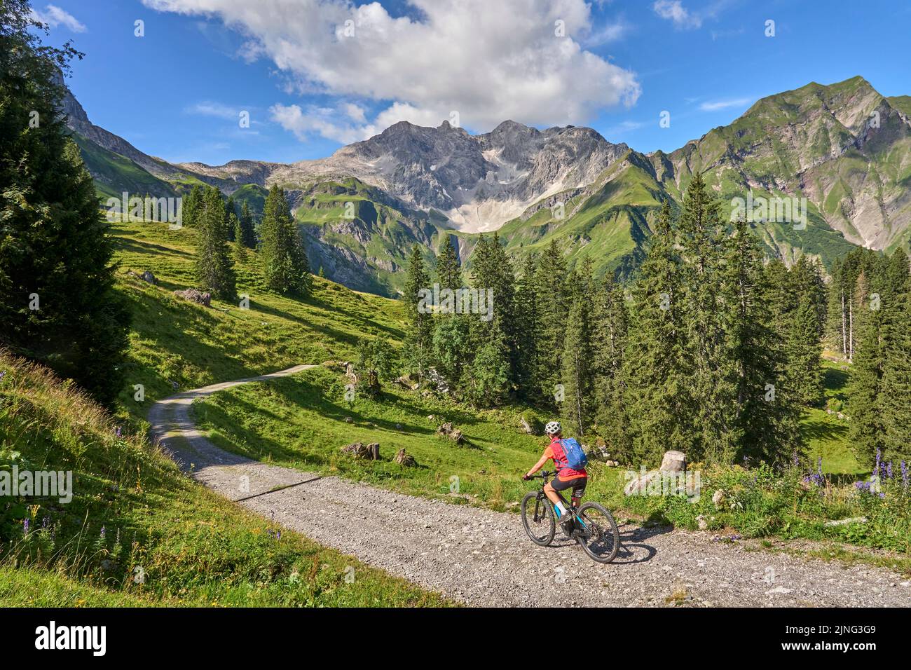 active senior woman, riding her electric mountain bike in the Arlberg mountain range near the famous village of Lech, Tirol, Austrian Alps Stock Photo