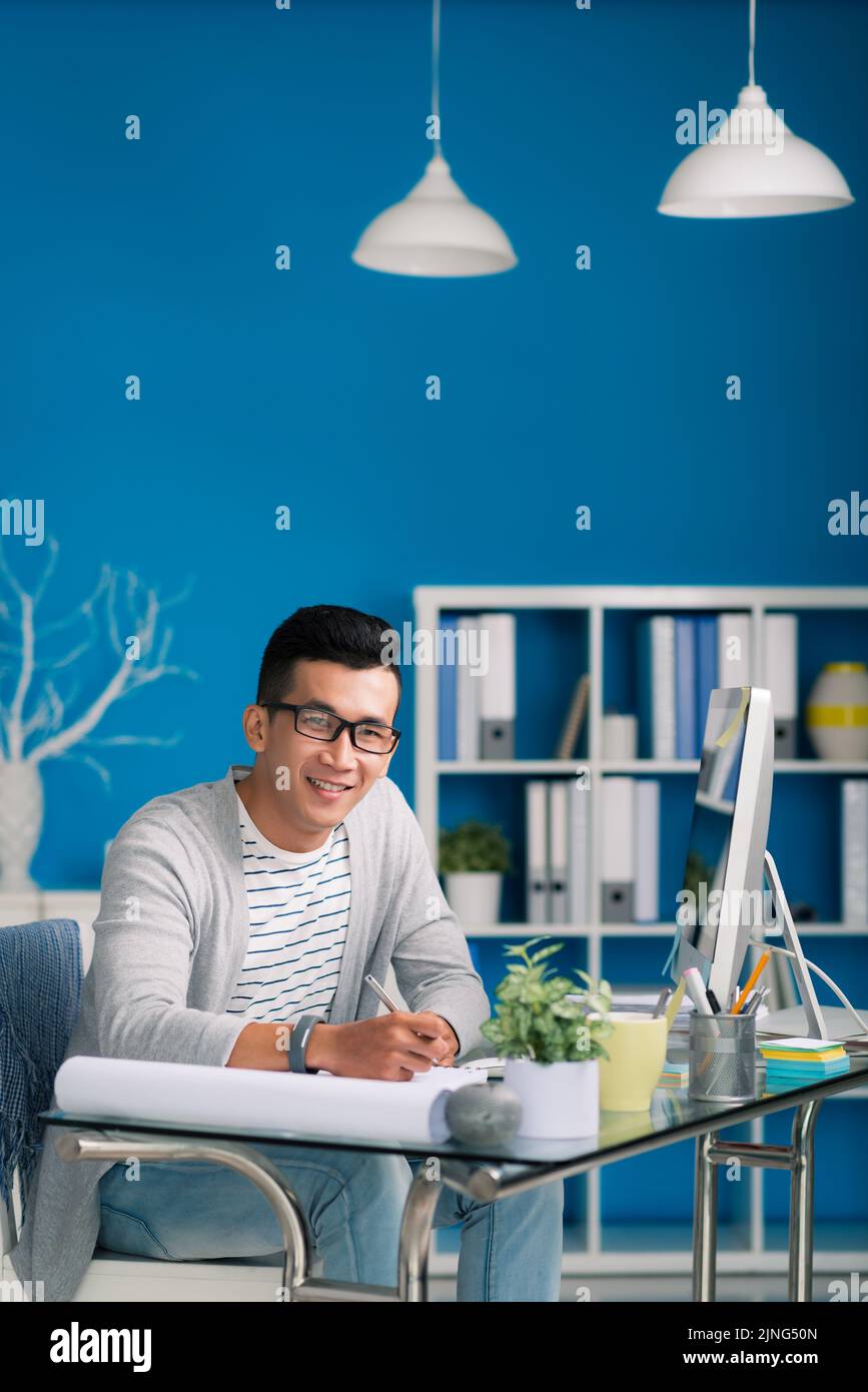 Smiling young engineer working on new project at his table Stock Photo