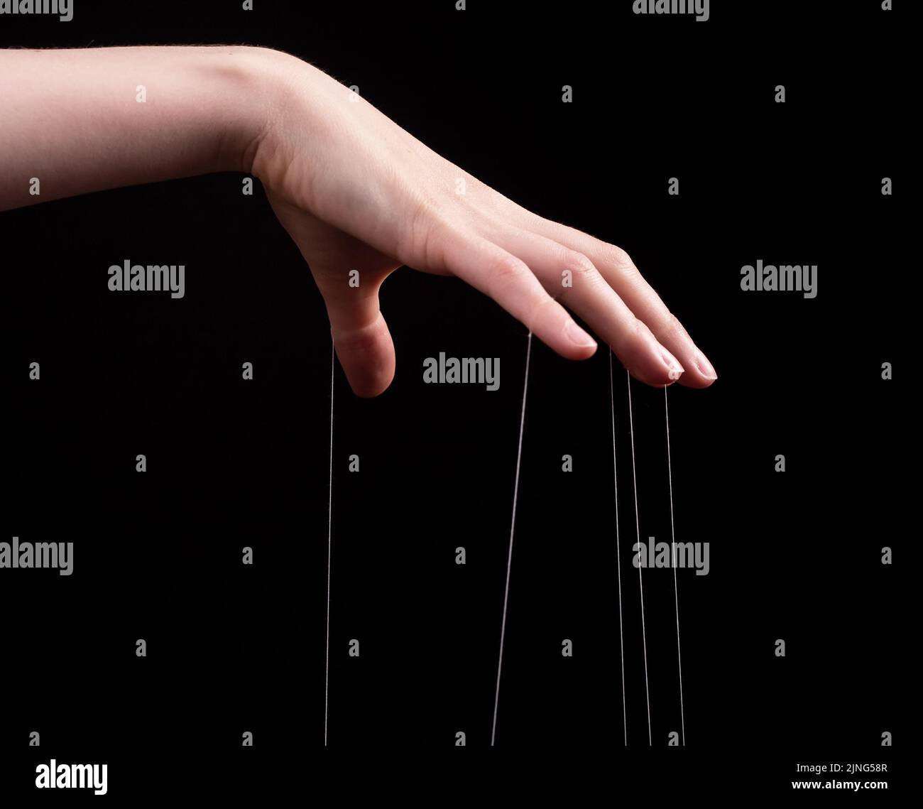 Manipulation, abuse concept. Female hand pulling strings on black