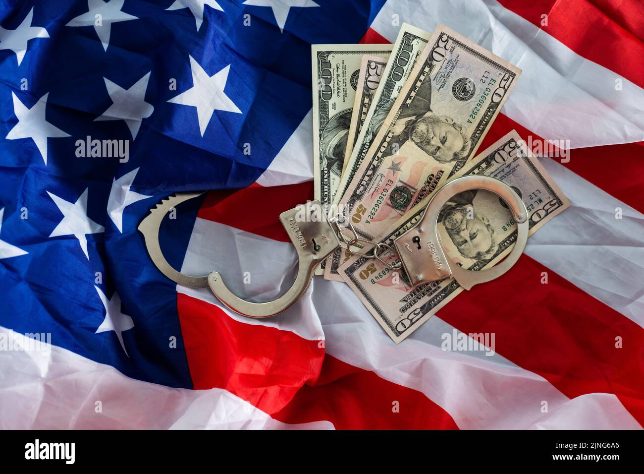 metal handcuff, american dollars cash over flag of USA. Illegal concept. Bribing and corruption Stock Photo