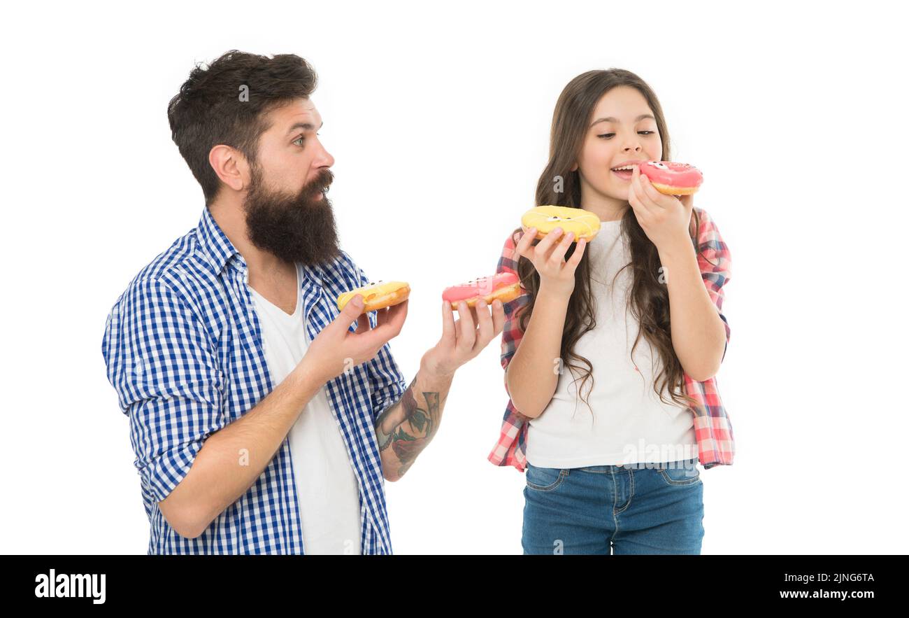 Sharing donuts for two. Bearded man and little girl holding ring donuts. Father and small daughter child eating tasty glazed donuts. Hipster and Stock Photo