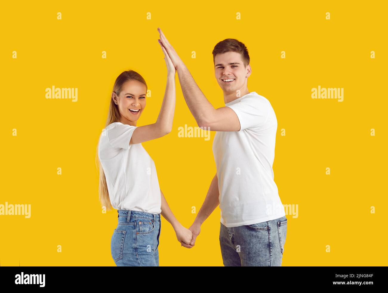 Young happy Caucasian couple man and woman give each other five and with smile look at screen Stock Photo