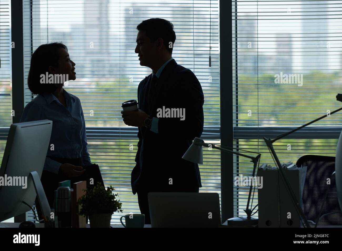 Cheerful colleagues talking during break in dark office Stock Photo