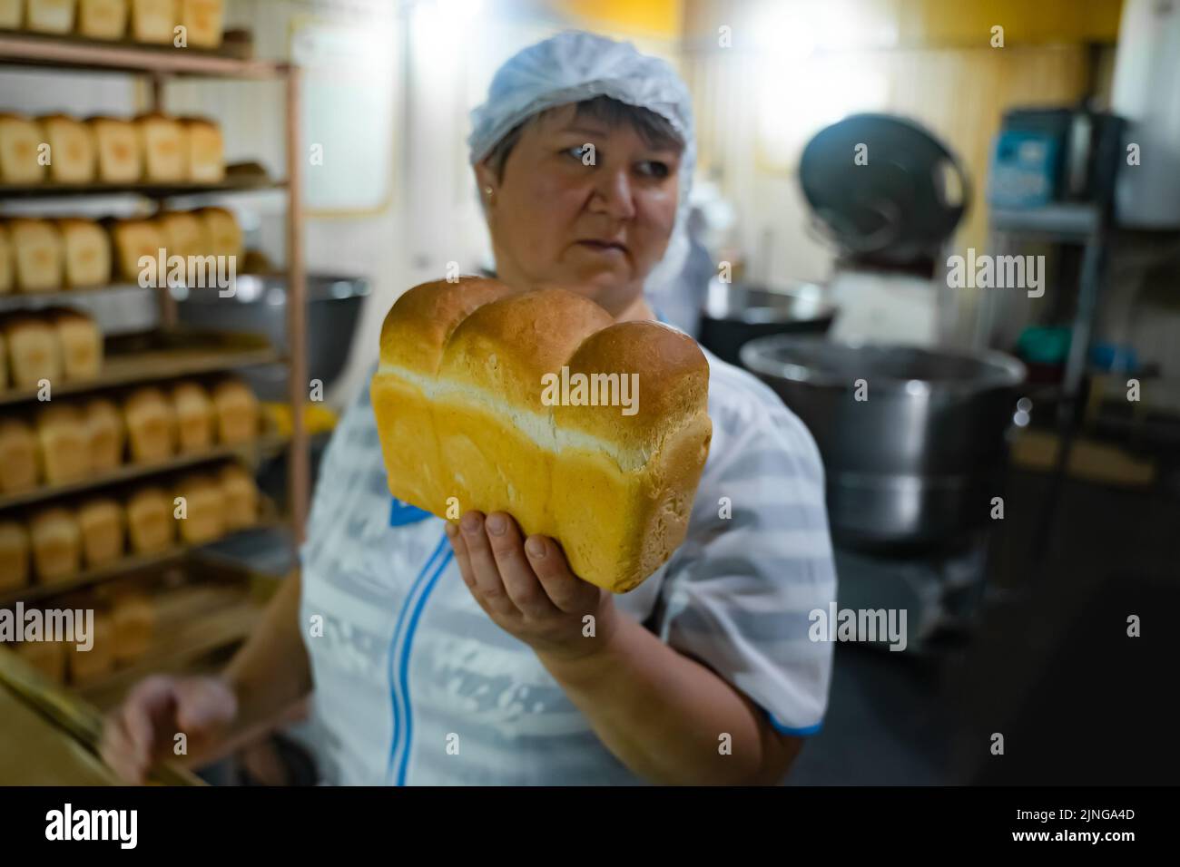 Tatarastan, Russia. 2022, 16 July. A bakery worker demonstrates a freshly baked loaf of bread. Bread production on a commercial scale Stock Photo
