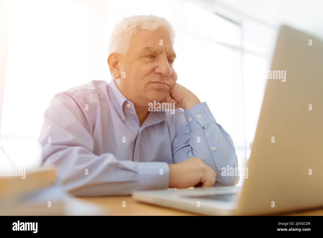 Sad aged man reading e-mails on laptop Stock Photo