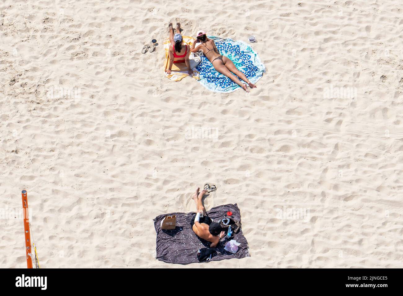 Beach goers enjoy summertime in Tel Aviv. Tel Aviv, located along the Mediterranean coastline, is Israel's cultural hub and a major travel destination that attracts tourists from around the world. Stock Photo