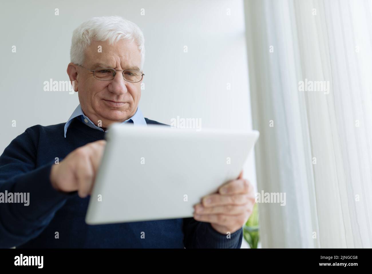 Senior man in glasses learning how to use tablet computer Stock Photo