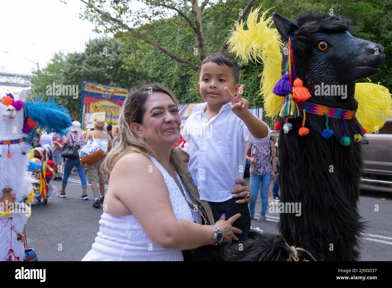 A vendor and her son at a stand with a wooden animal statue. At the