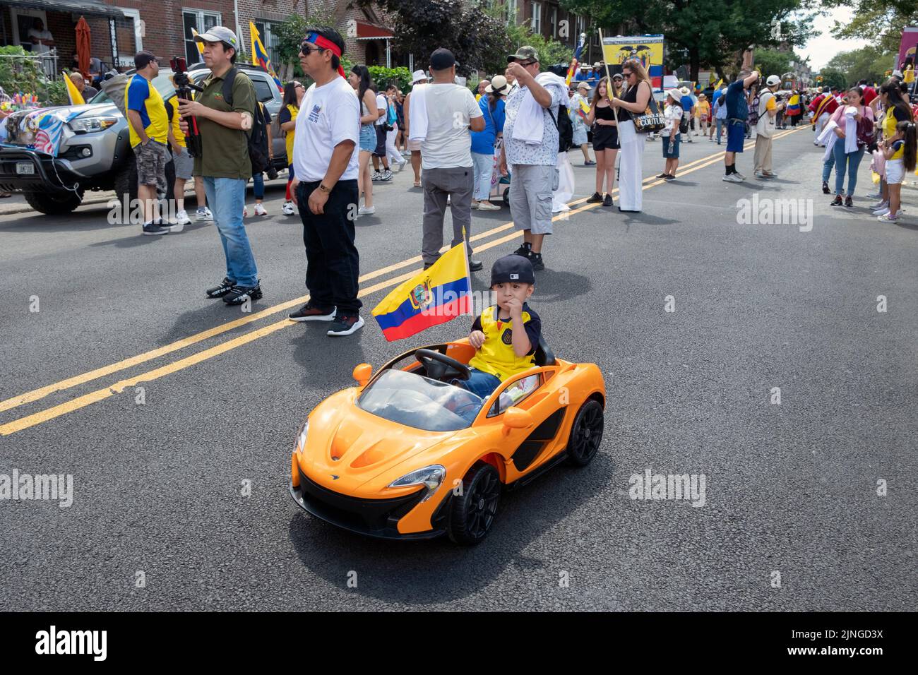 A young Ecuadorian boy rides his electric car on 69th Street just prior to the Ecuadorian Parade NYC 2022 in Jackson Heights, Queens, New York. Stock Photo