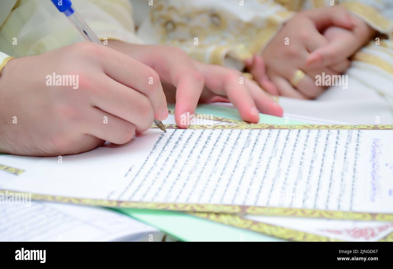 Husband signs the marriage document. Stock Photo