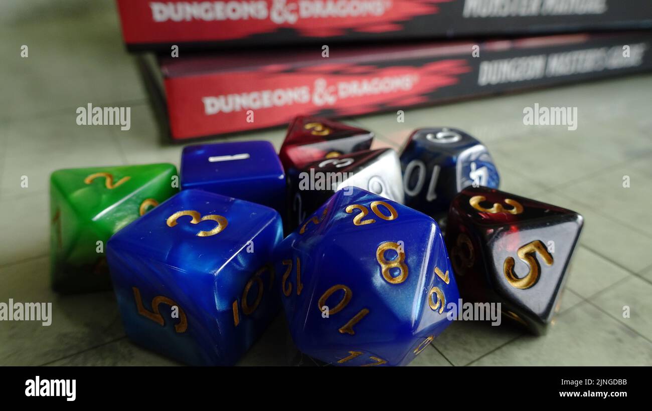A closeup shot of several dice with Dungeons and Dragons books behind them Stock Photo