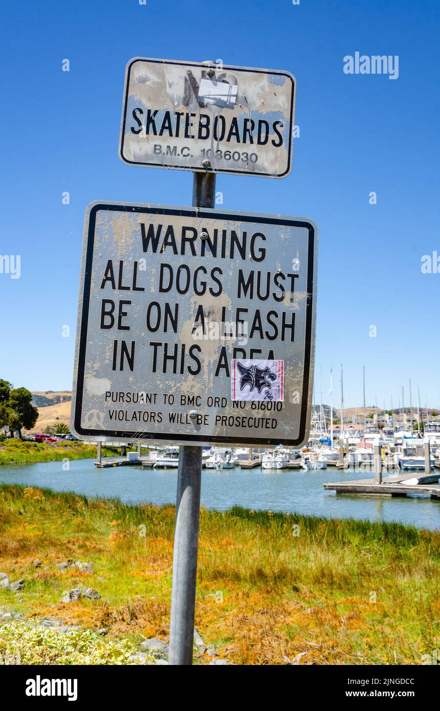Signs at Benicia Marina in California, USA warn people to keep dogs on a leash and give notice that no skateboards are allowed. Stock Photo