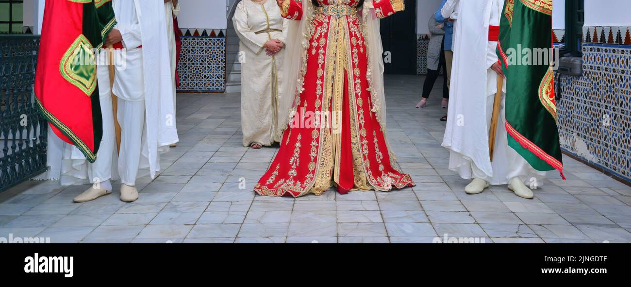 A bride wearing a red Moroccan caftan walking to her groom Stock Photo
