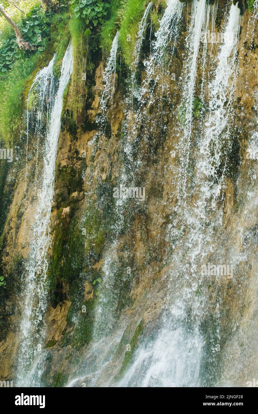 Waterfall majestic view with water streams of pure crystal foamy water jets in national park. Landscape with lush plants and rocks on Plitvice lakes Stock Photo