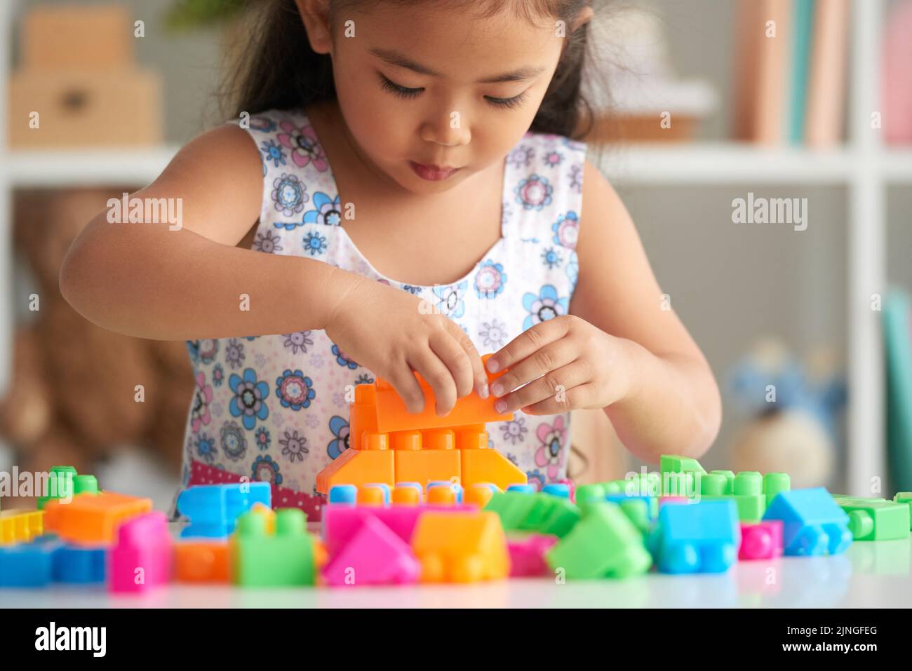 Little Asian Girl Concentrated On Building A Tower From Plastic Bricks little-asian-girl-concentrated-on-building-a-tower-from-plastic-bricks