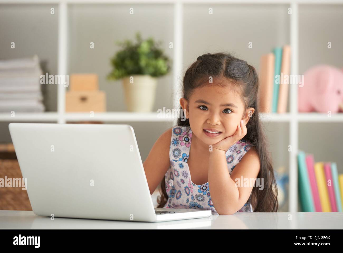 Cute cheerful little girl working on laptop Stock Photo - Alamy