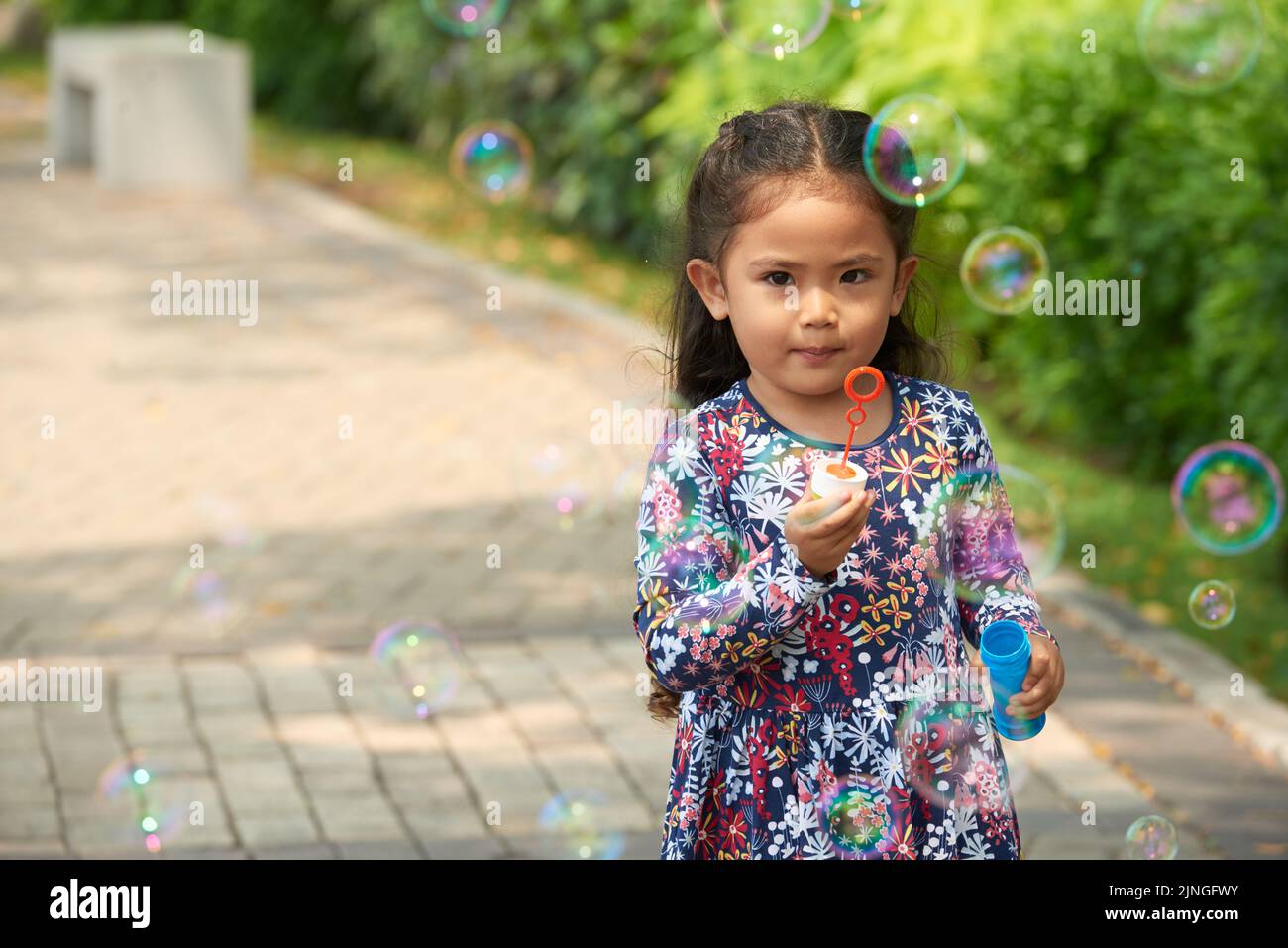 Portrait of little girl blowing soap bubbles in summer park Stock Photo ...
