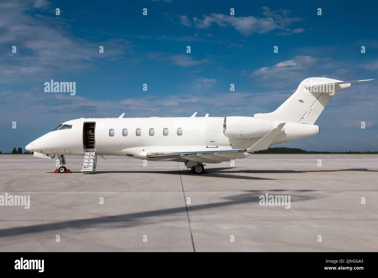 Modern white business jet with an opened gangway door at the airport apron Stock Photo
