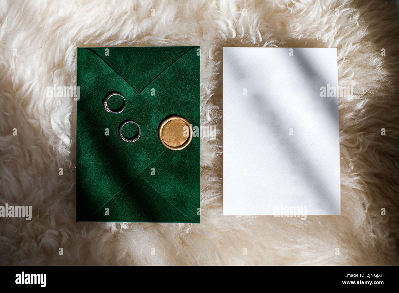 Two wedding rings on a green invitation envelope. Stock Photo
