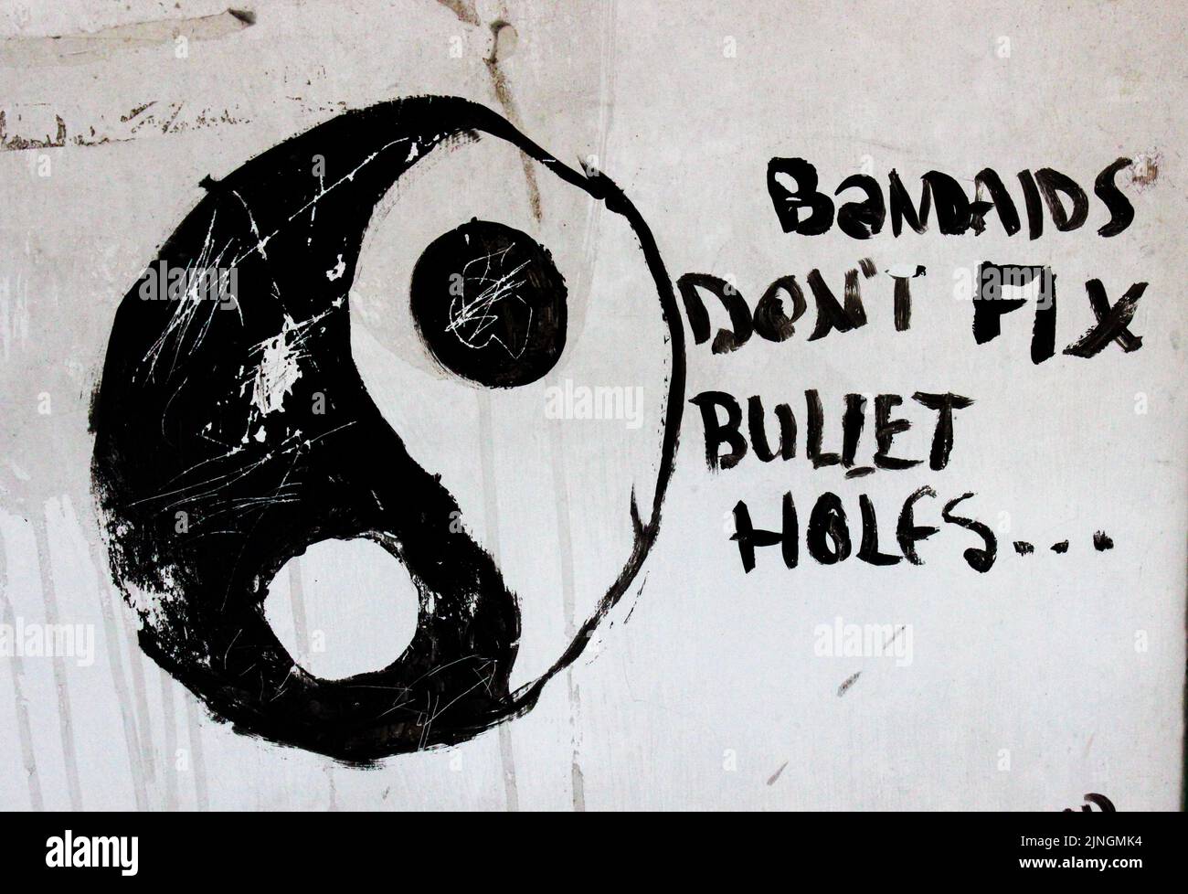 A yin and yang symbol with an anti-war Bandaids don't fix bullet holes quote Stock Photo