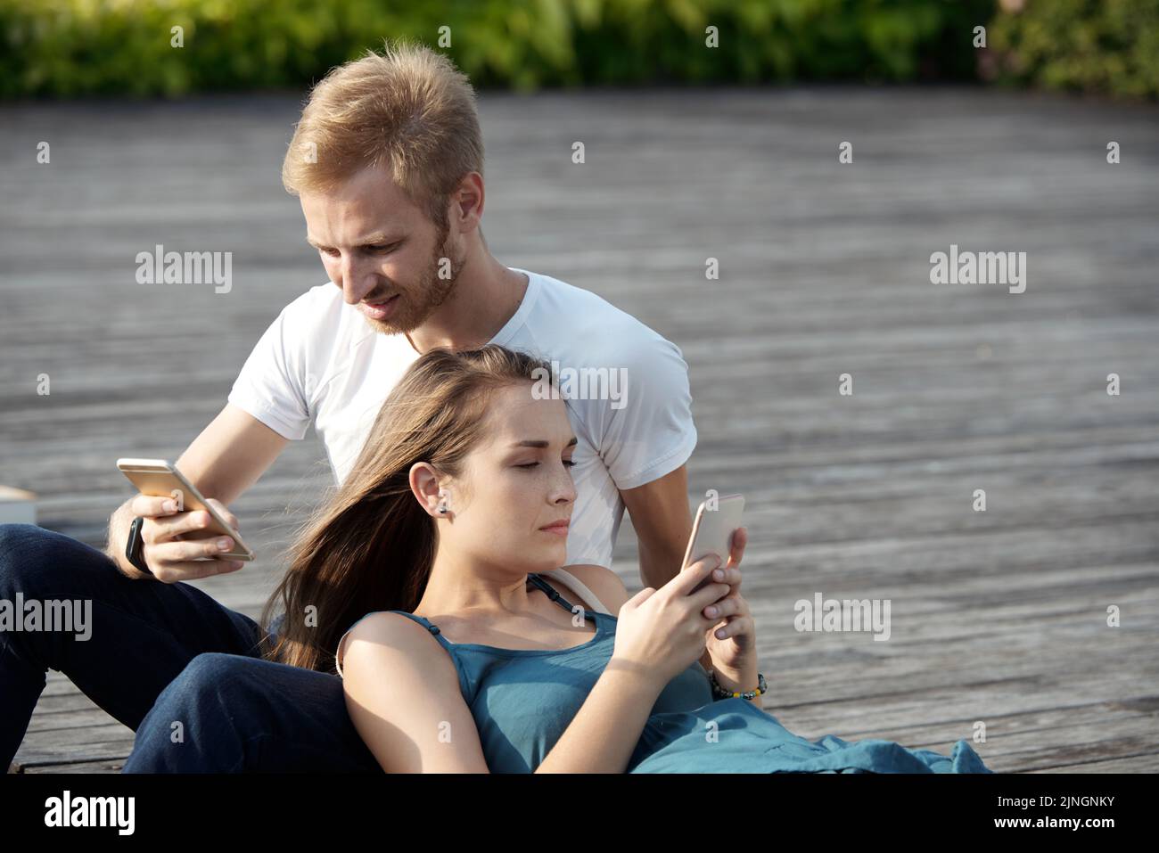 Young couple using their smartphones while spending time together outdoors Stock Photo