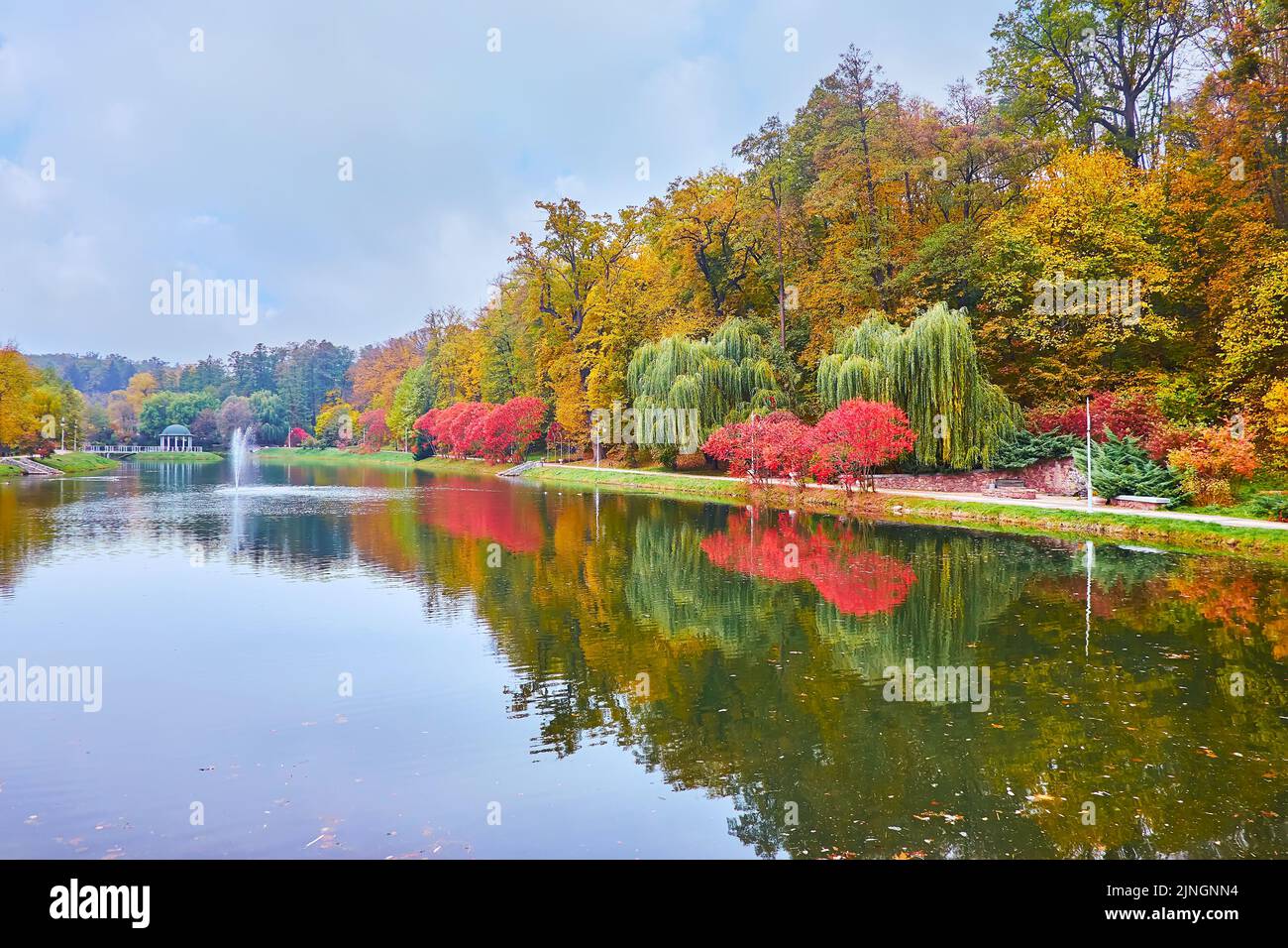 The bright red, yellow and green autumn trees on the bank of Palladin pond in Feofania park, Kyiv, Ukraine Stock Photo