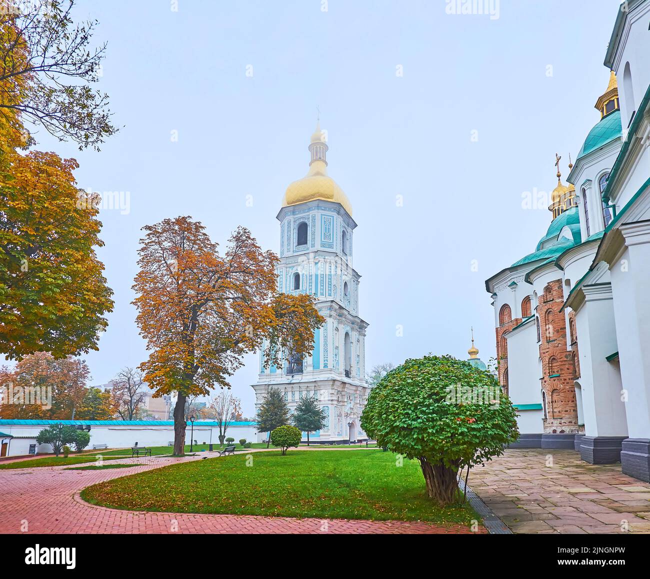 The foggy autumn weather in scenic park of St Sophia National Sanctuary with a view on medieval bell tower, topped with a golden dome, Kyiv, Ukraine Stock Photo