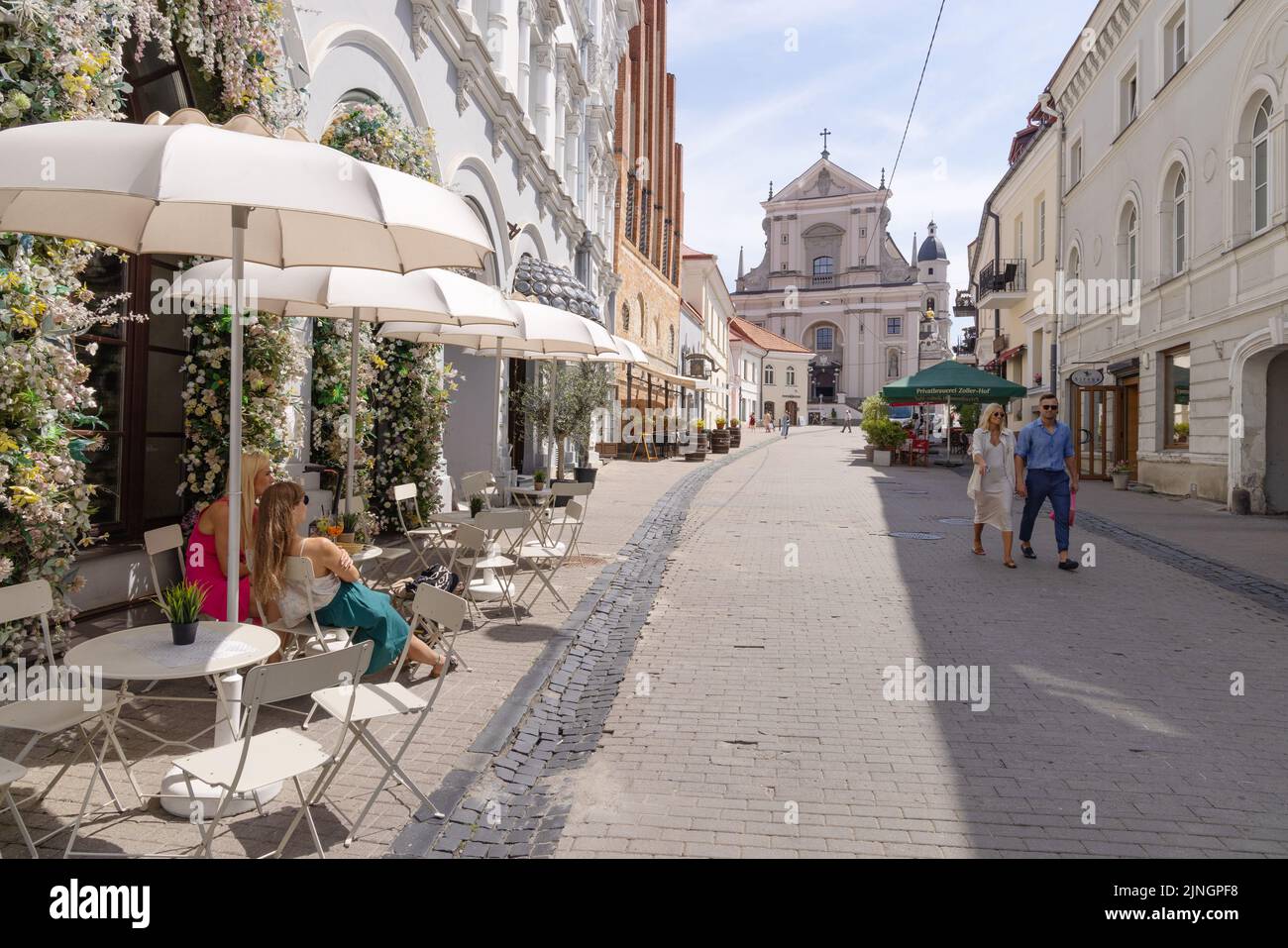 Lithuania travel; Vilnius Old Town street scene with the Church of St Theresa and people at a cafe; Vilnius, Lithuania Europe Stock Photo