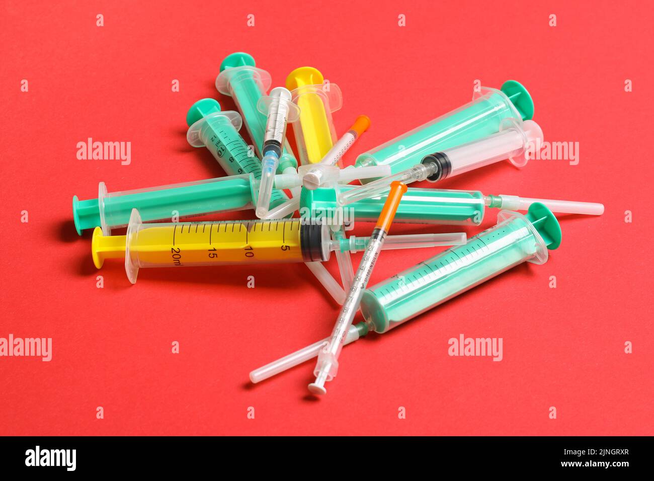 Top view of a heap of syringes and insulin syringes at red background. Medical injection concept
