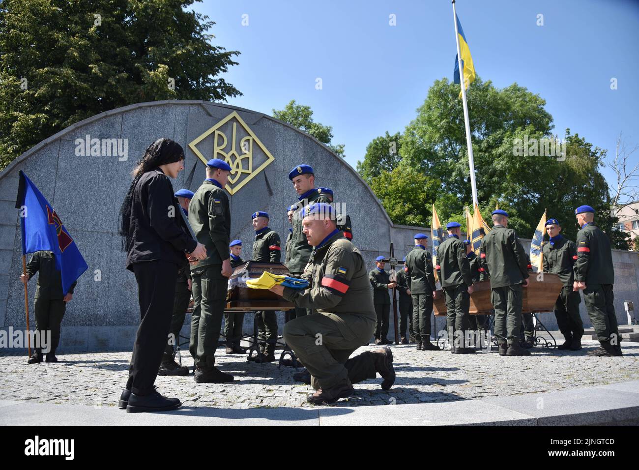 A military officer hands the flag of Ukraine to the civilian wife of