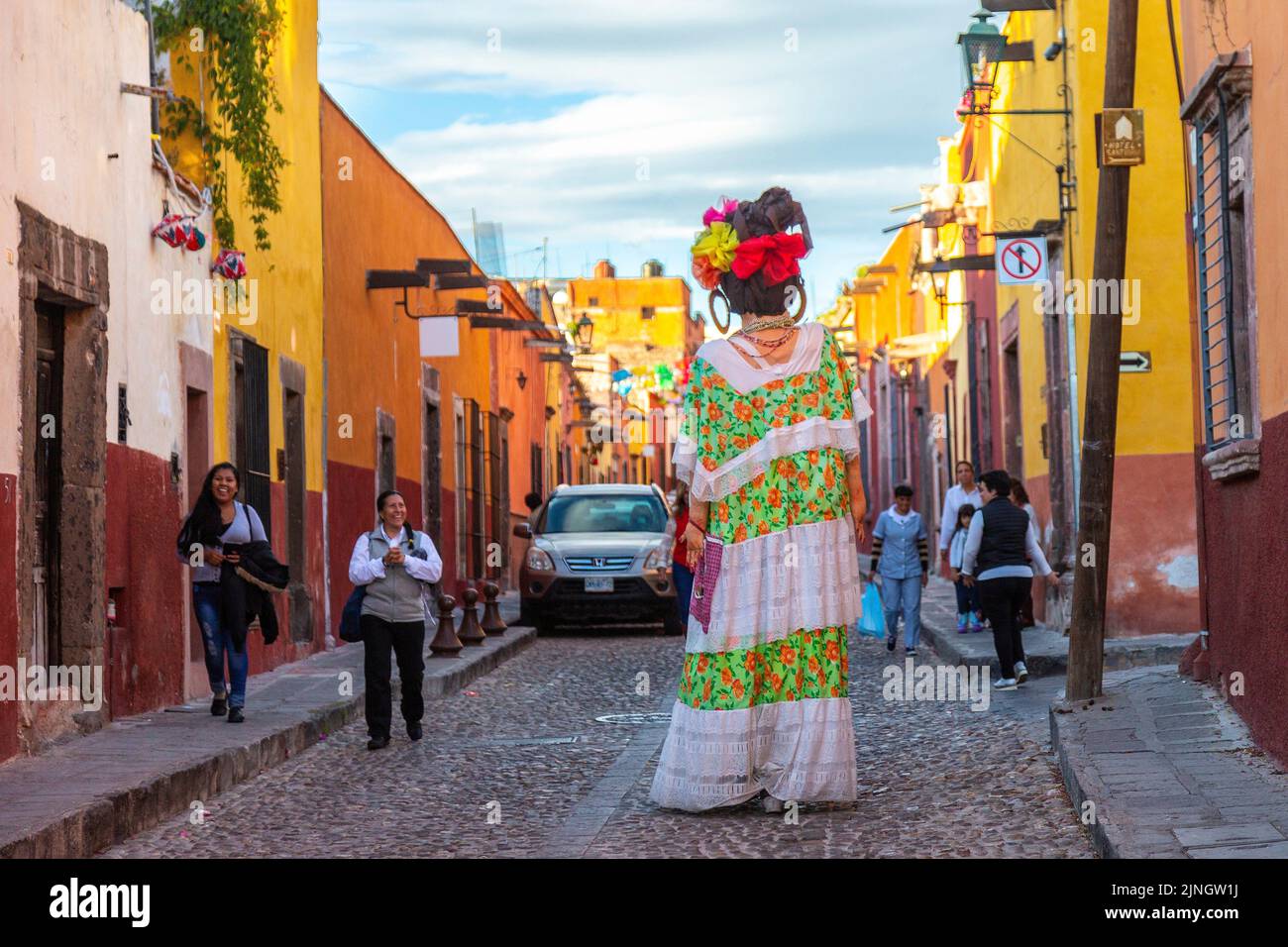 People react to seeing a mojiganga, or giant puppet made from papier mâché as it walks through the historic city center of San Miguel de Allende, Mexico. Stock Photo