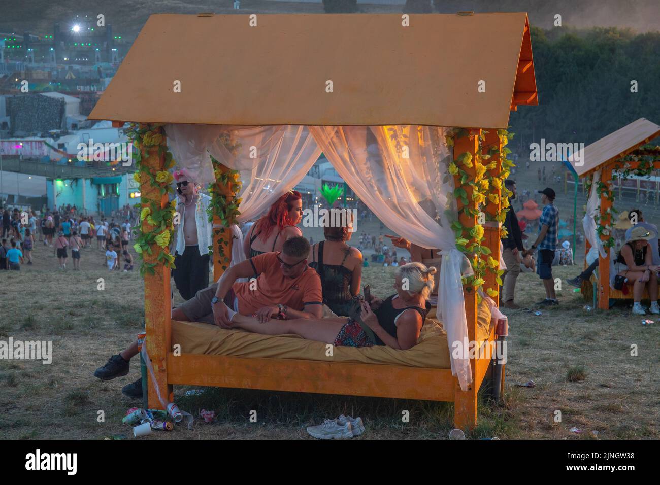 Boomtown, Winchester, UK 11 August 2022 Campers arrive in a heatwave at Boomtown Festival. Seeking water and shade wherever they can find it and heading out on mass as the sun sets. Stock Photo