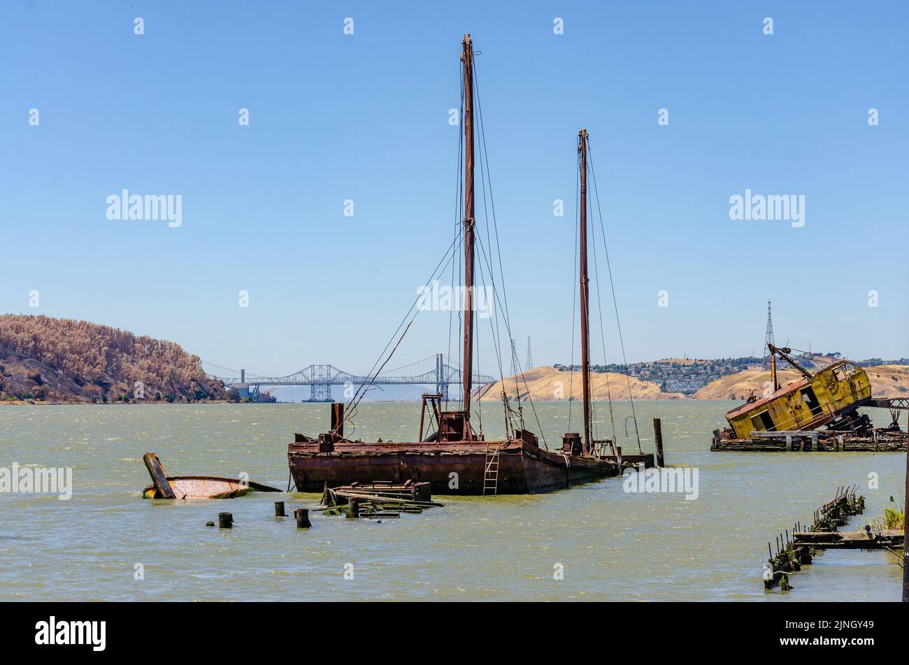 A view from Benicia across the Carqunez Strait with a sunken boat in the foreground and the Alfred Zampa Memorial Bridge in the distance in California Stock Photo