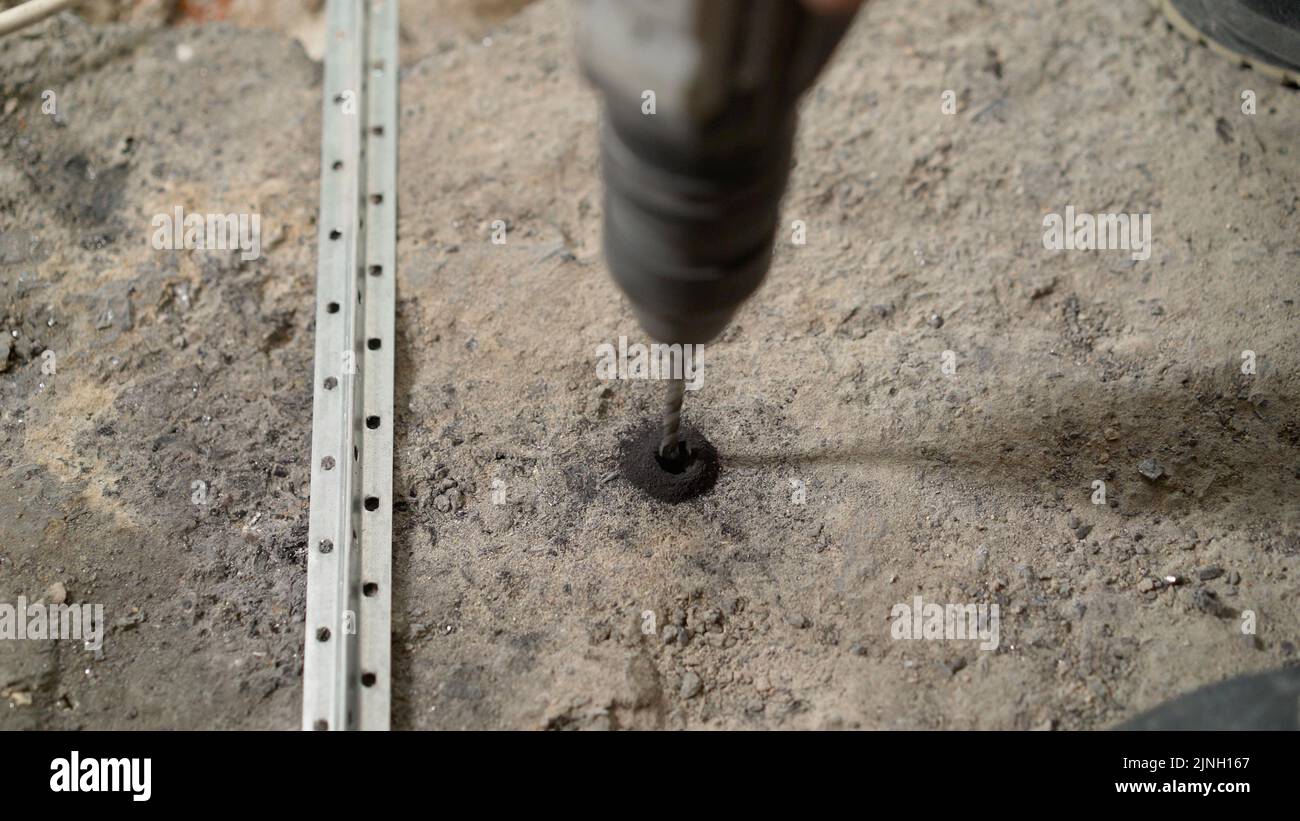 A builder drills a concrete floor. The cementconcrete floor was