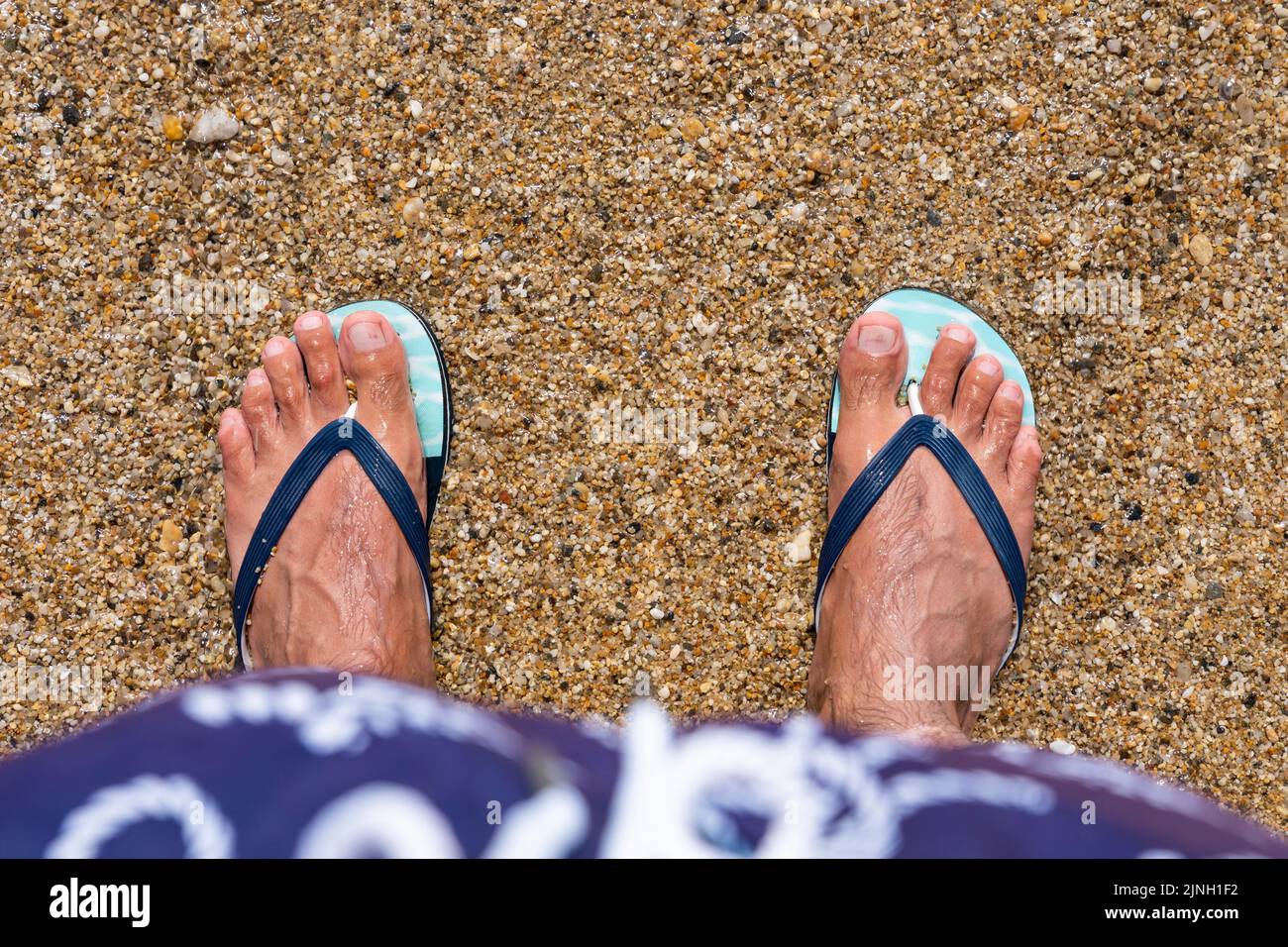 Mans feet in flipflops at the beach. Top view. Flat lay. Copy space