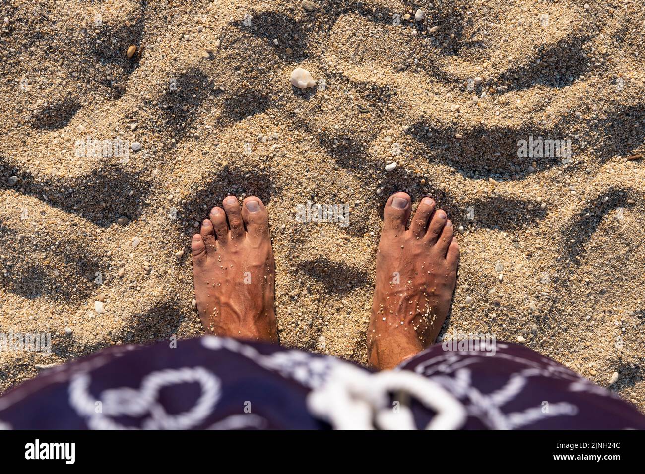 Barefoot standing at the beach. Mans feet on sandy beach. Top view. Blank space for text or logo Stock Photo
