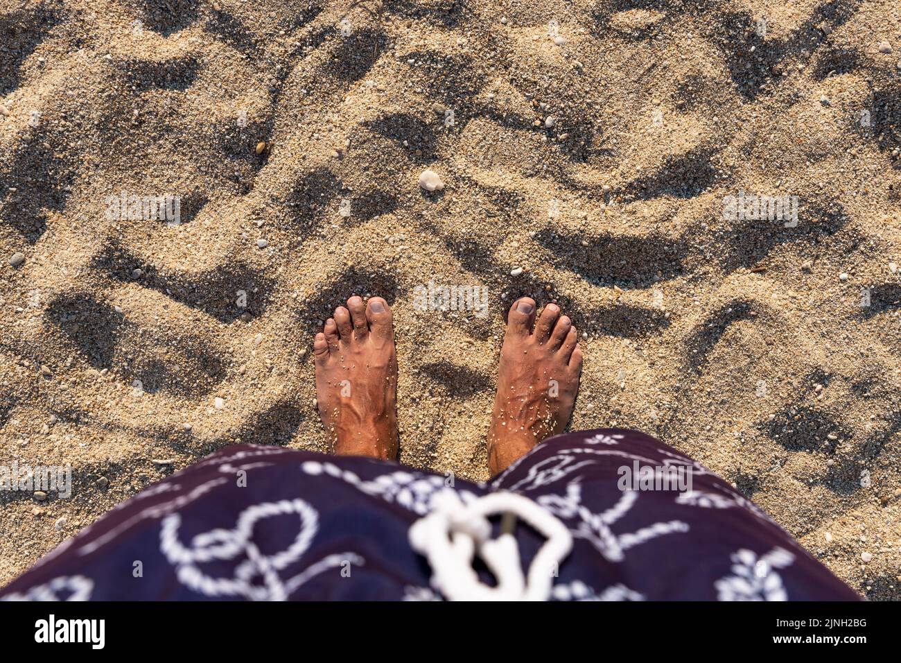 Barefoot standing at the beach. Mans feet on sandy beach. Top view. Blank space for text or logo Stock Photo